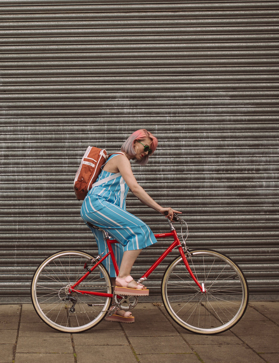 Classic orange backpack Goodordering on bicycle in front of a metal garage door cycling bag