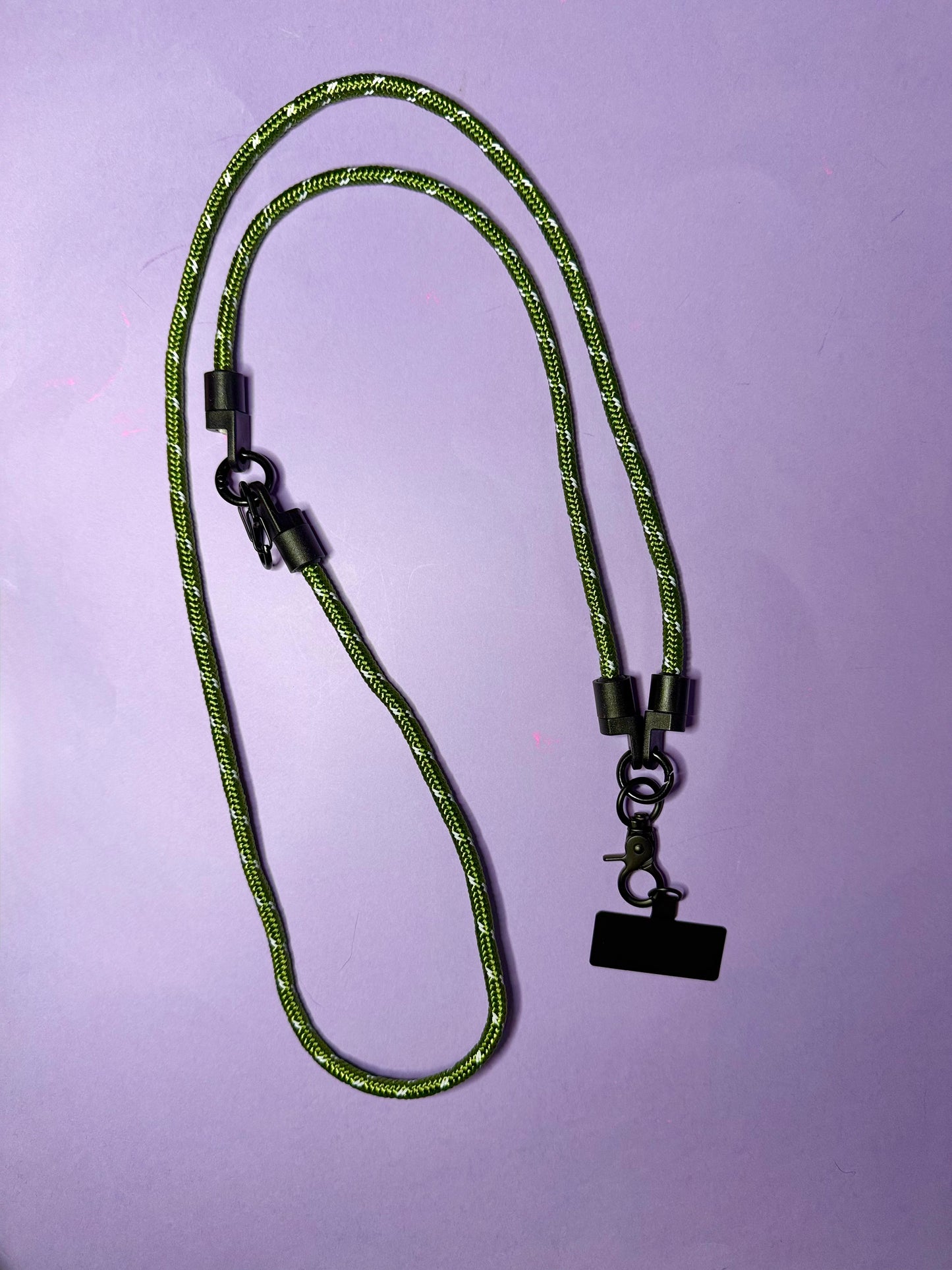 Green braided lanyard with black metal clip on a purple background