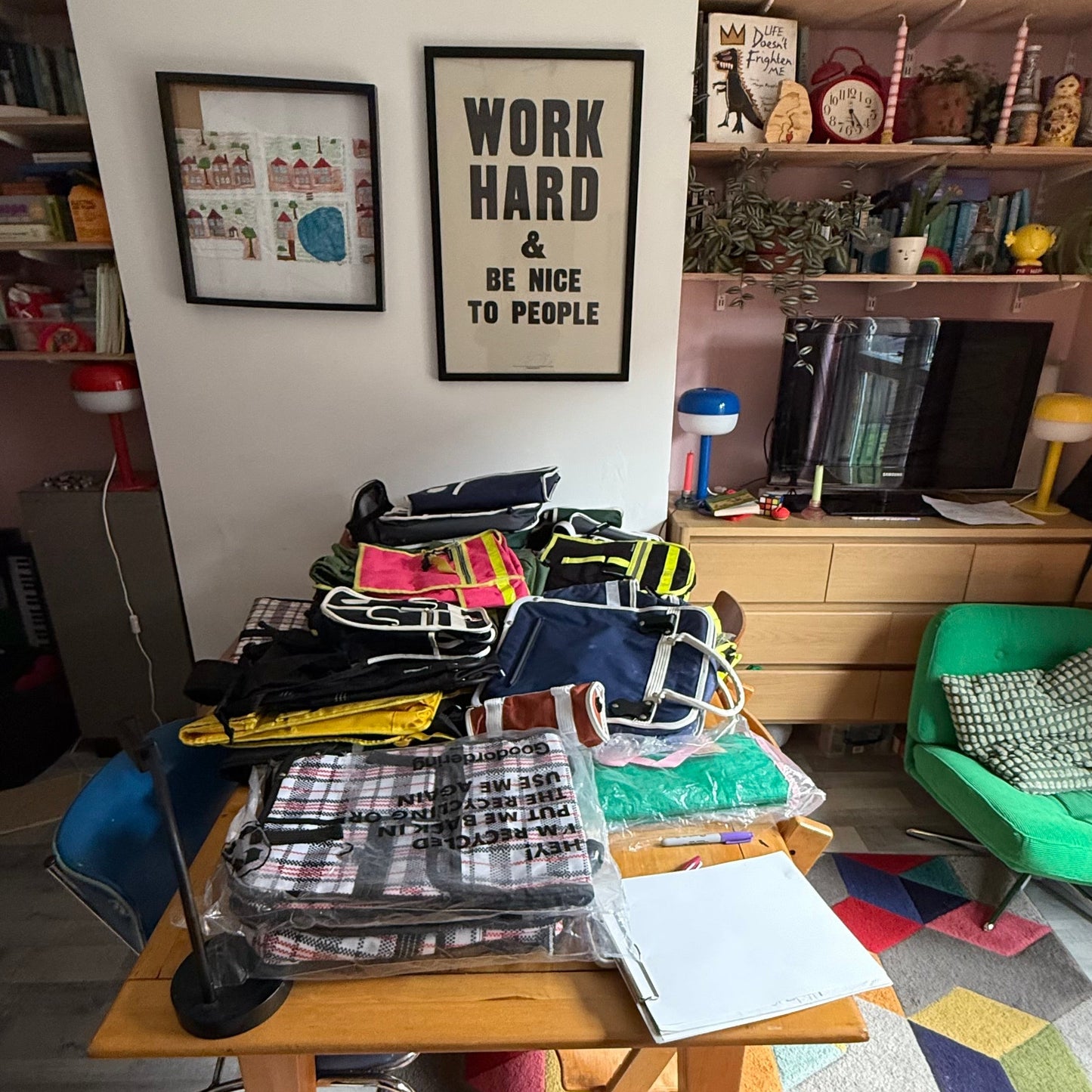 Cluttered room with a table, books, and colorful rug.