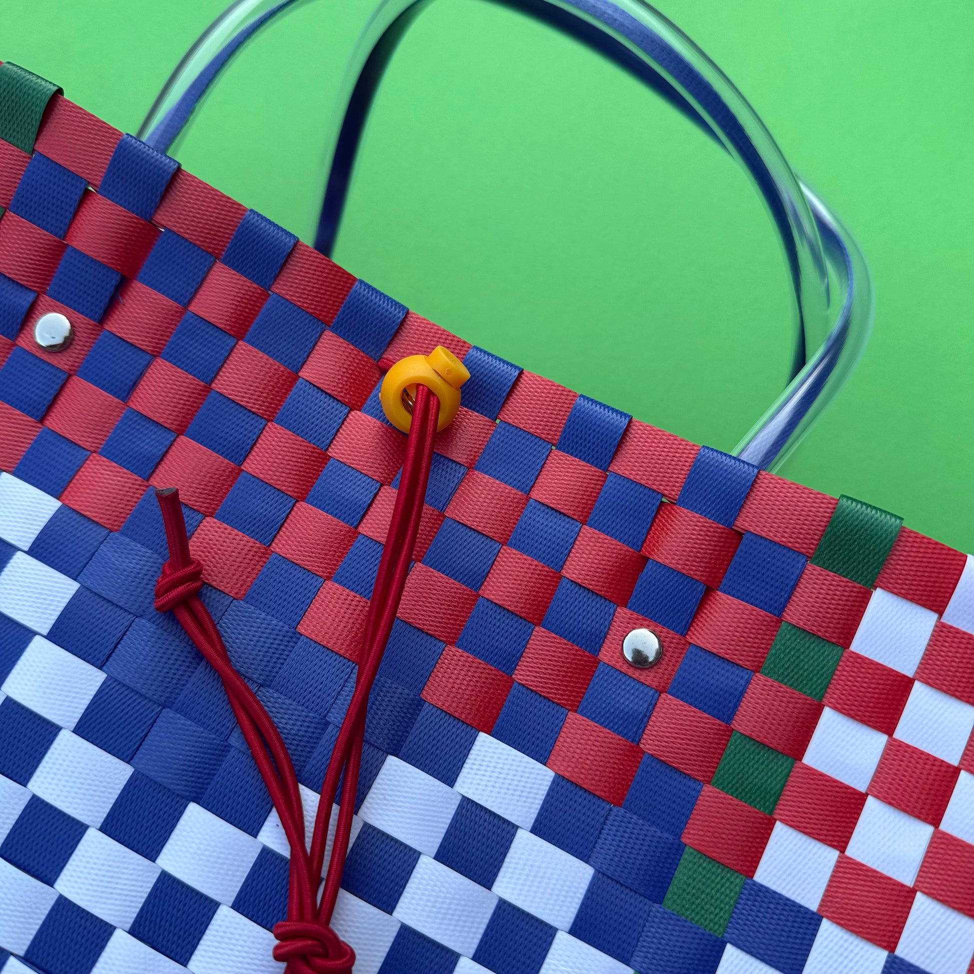 Close-up of a woven bag with a colorful checkered pattern on a green background