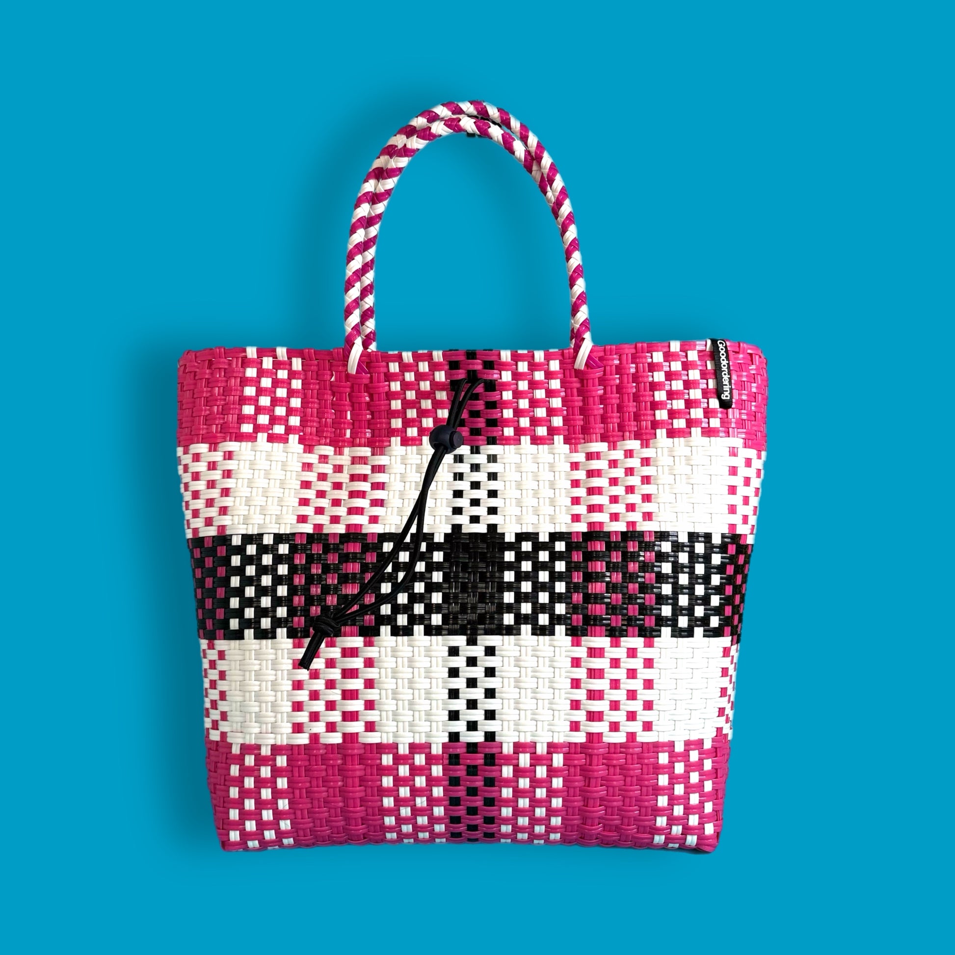 Woven tote bag with pink, white, and black pattern on a blue background