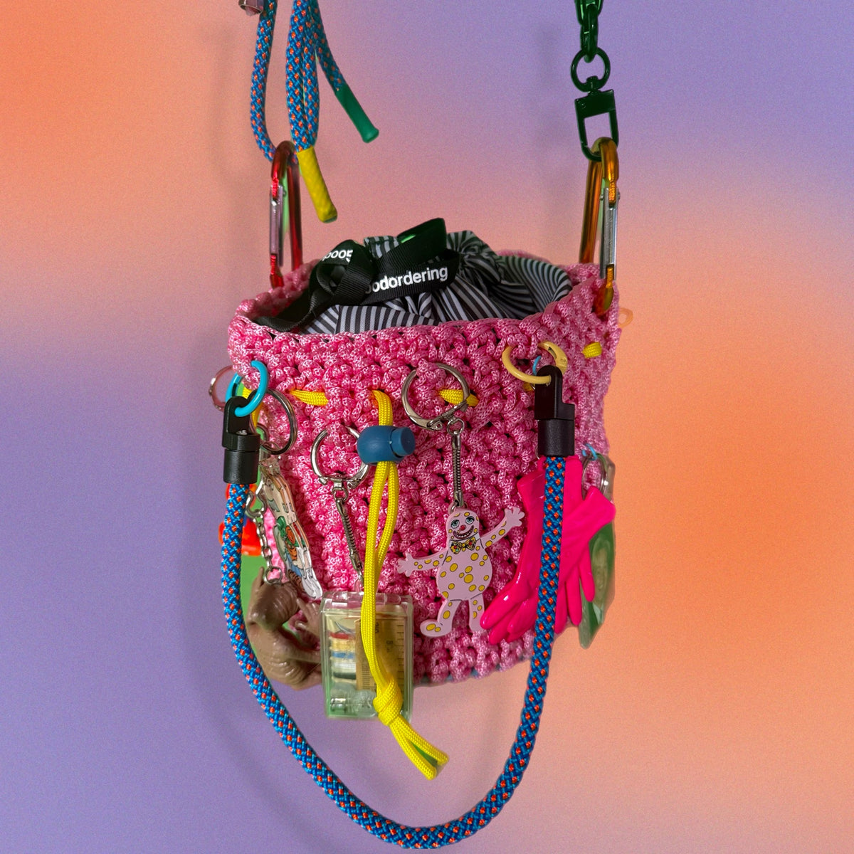 crocheted Pink chalk bag with various keys and items on a gradient background