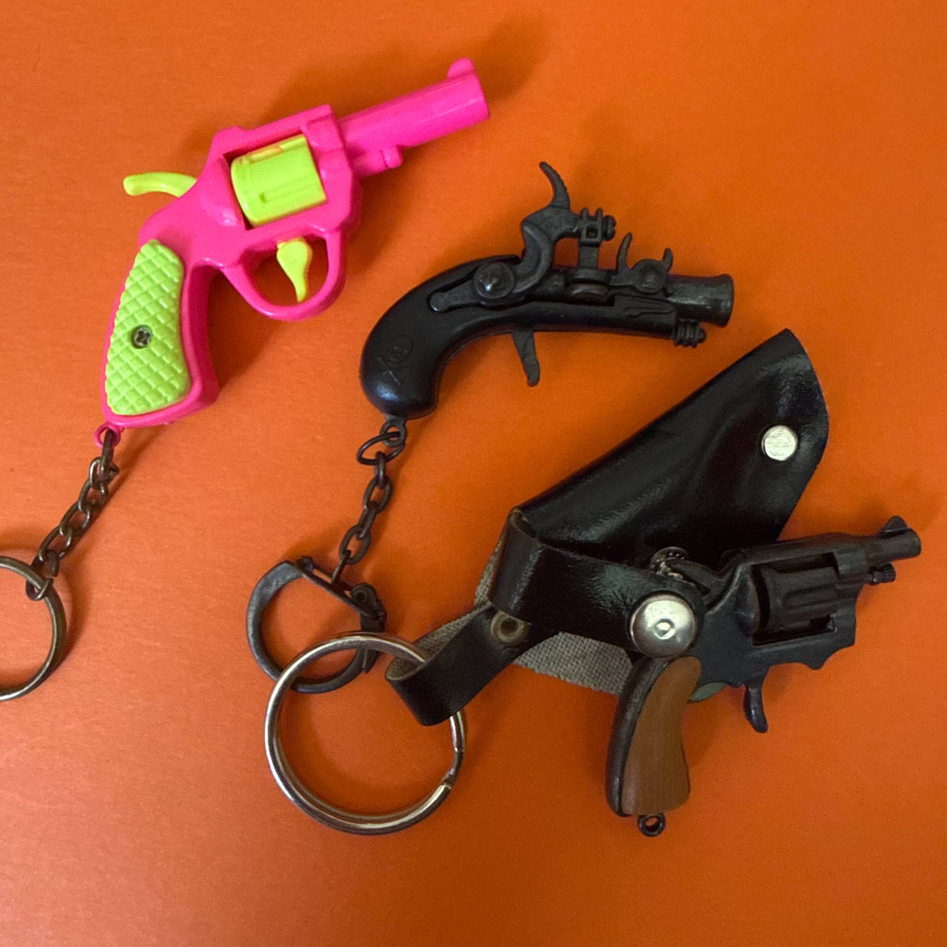 Toy gun keychain with pink and green design on an orange background