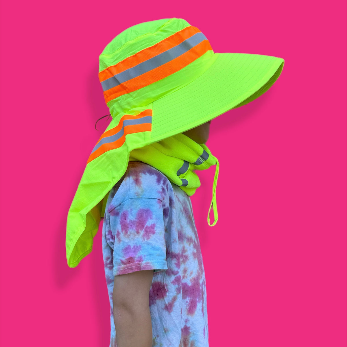 Person wearing a bright yellow sun hat with orange and gray reflective stripes on a pink background