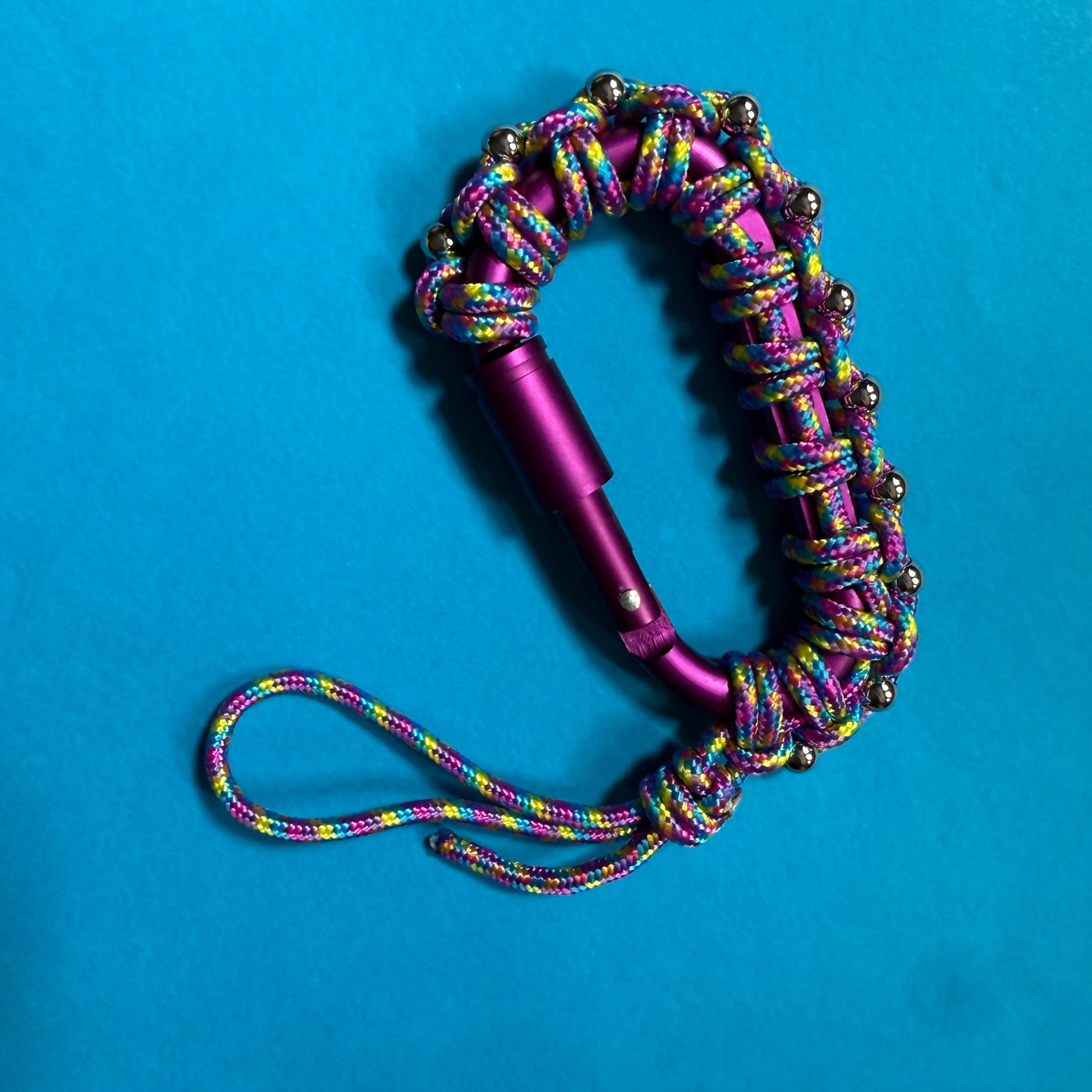 Multicolored paracord keychain with purple carabiner on a blue background